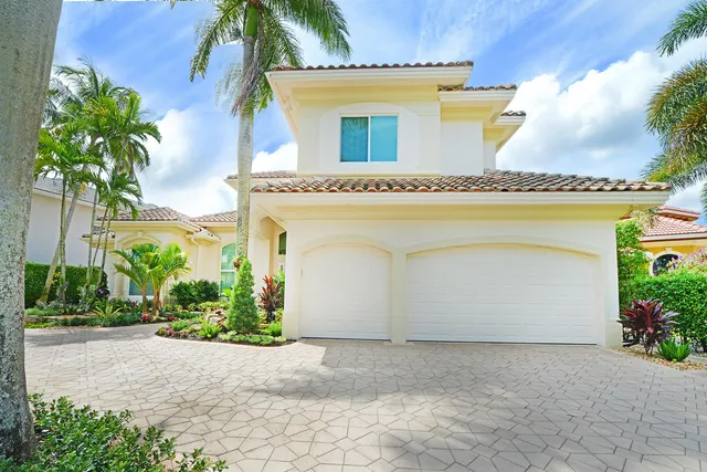 a front view of a house with a garden and palm trees