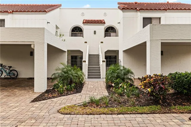 a view of white house with wooden walls and potted plants