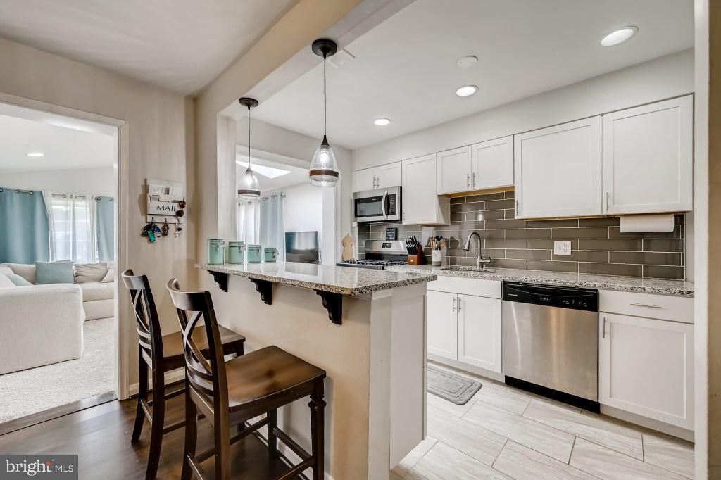8023 Wallace Road Baltimore, MD 21222 - Photo 3 of 21 a kitchen with stainless steel appliances granite countertop white cabinets a sink a stove a dining table and chairs