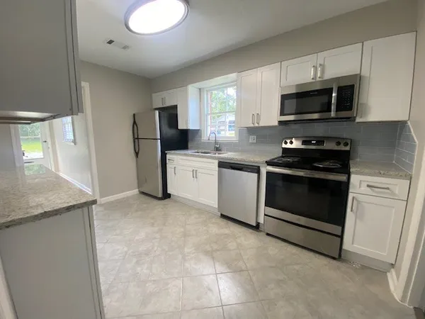 a kitchen with stainless steel appliances granite countertop a stove a sink and a microwave