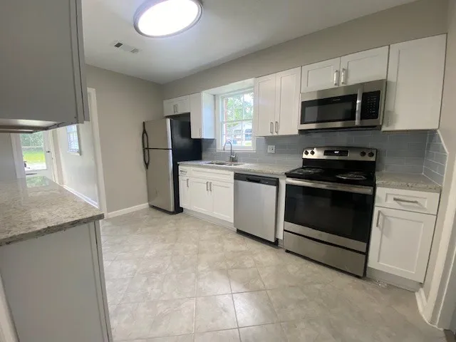 a kitchen with stainless steel appliances granite countertop a stove a sink and a microwave