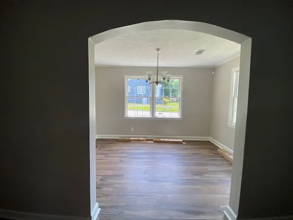 an empty room with wooden floor and chandelier