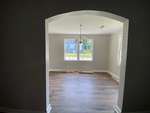 an empty room with wooden floor and chandelier