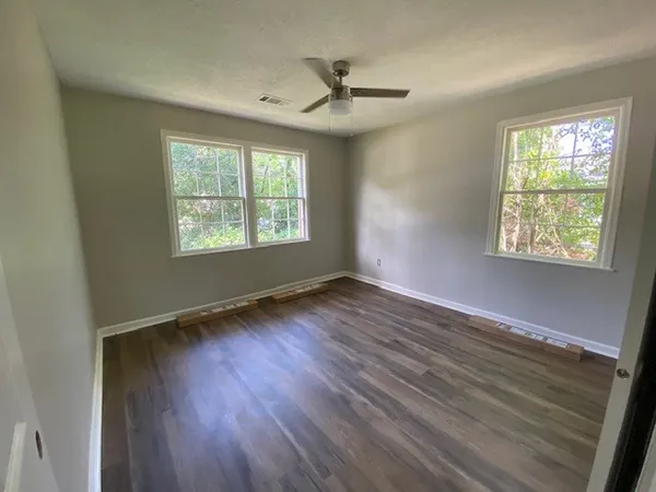 a view of an empty room with wooden floor and a window