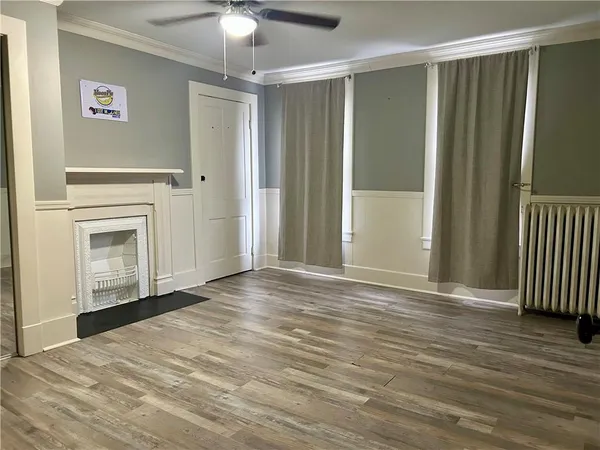 a view of empty room with wooden floor and fan