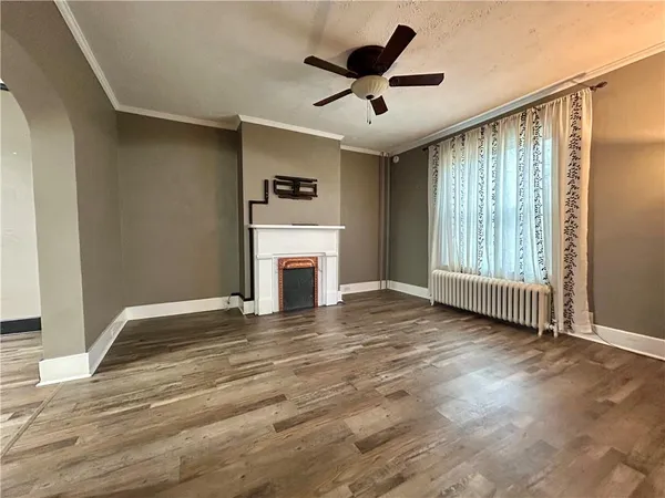 a view of an empty room with a window and a kitchen