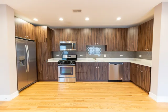 a kitchen with kitchen island granite countertop wooden cabinets a refrigerator and a sink