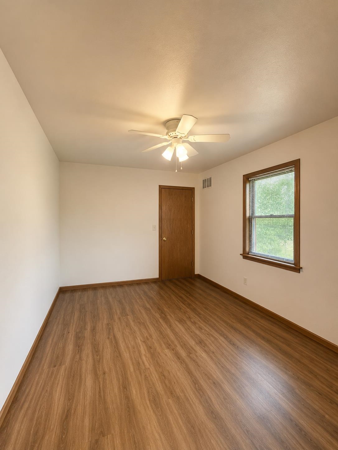 3960 West Union Road Millington, TN 38053 - Photo 6 of 10 Room featuring wood-finish flooring, a white ceiling fan with integrated lighting, white walls, and a window with wood trim