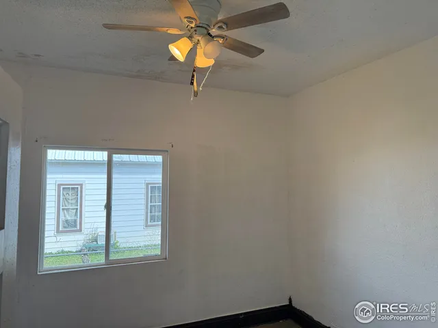 an empty room with a window and a fan