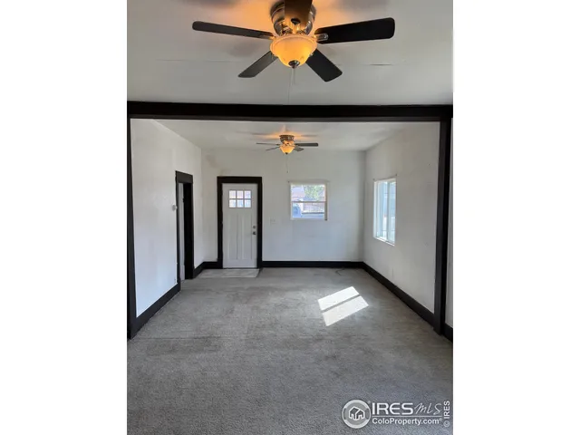 a view of an empty room with window and chandelier fan
