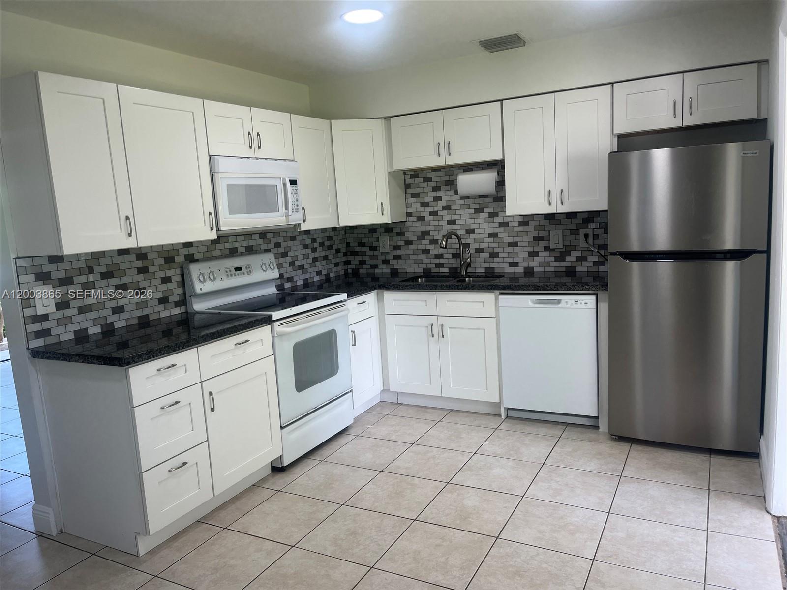 753 Southwest 3rd Street Dania Beach, FL 33004 - Photo 2 of 16 a kitchen with white cabinets a refrigerator and a sink