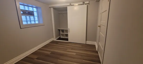 a view of an empty room with closet and a window