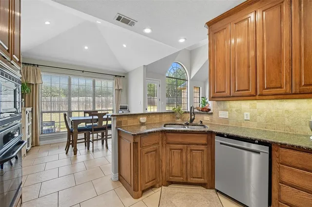 a kitchen with stainless steel appliances granite countertop a sink a stove and a refrigerator