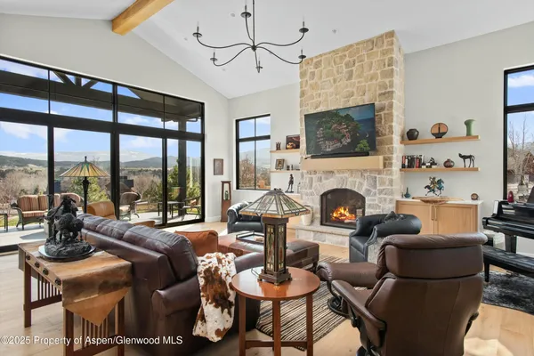 a living room with furniture a fireplace and a floor to ceiling window