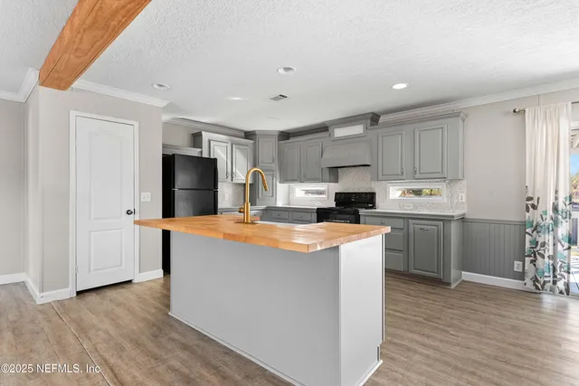a kitchen with stainless steel appliances granite countertop a refrigerator a sink dishwasher a stove top oven a dining table and chairs with wooden floor