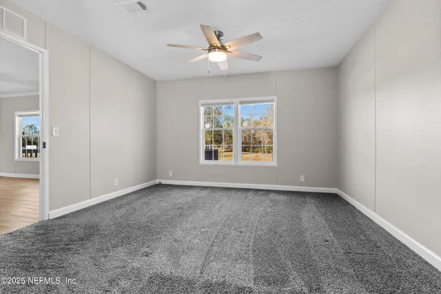an empty room with windows and ceiling fan