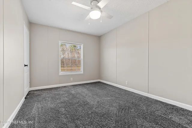 an empty room with a chandelier fan and windows