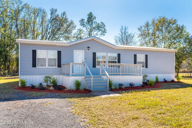 a front view of a house with a yard and potted plants