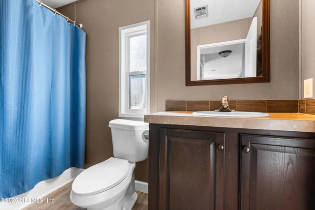 a bathroom with a granite countertop toilet sink and mirror