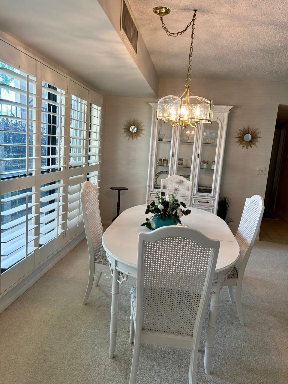 1 Southeast Turtle Creek Drive, Unit B Jupiter, FL 33469 - Photo 12 of 31 a dining room with furniture a chandelier and window