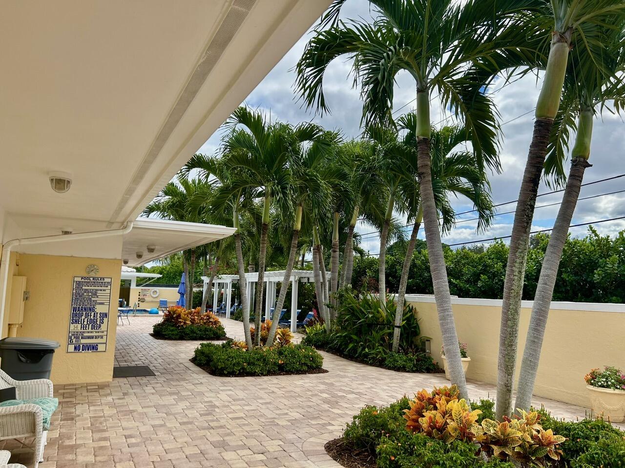1 Southeast Turtle Creek Drive, Unit B Jupiter, FL 33469 - Photo 31 of 31 a view of a patio with table and chairs potted plants and palm tree
