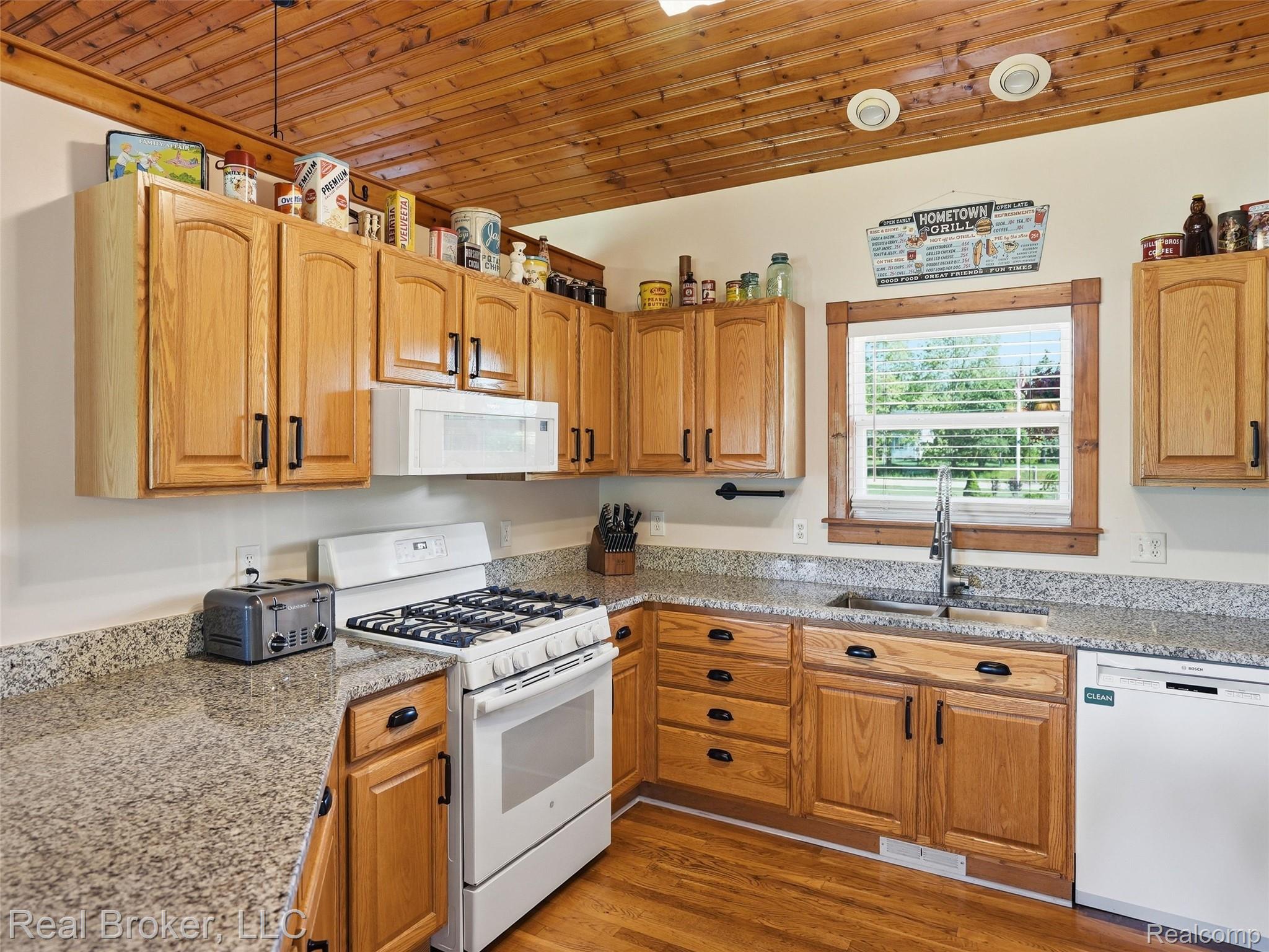 7271 West Ray Road Gaines, MI 48436 - Photo 26 of 48 Kitchen featuring wood-finish flooring, wood cabinetry with black hardware, and granite-style countertops