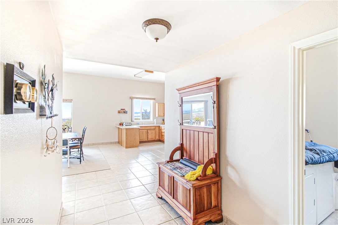 Rocking S Ranch Road Searchlight, NV 89046 - Photo 18 of 47 A well-lit hallway with tile flooring extends towards a casual dining area and kitchen, featuring scenic outdoor views.