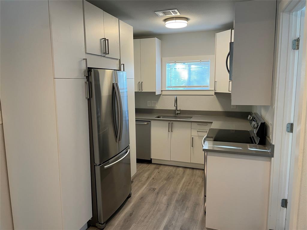 10310 Gail Road, Unit B Austin, TX 78748 - Photo 2 of 12 A streamlined kitchen showcasing modern appliances and durable wood-look flooring.