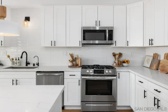 a kitchen with white cabinets and stainless steel appliances