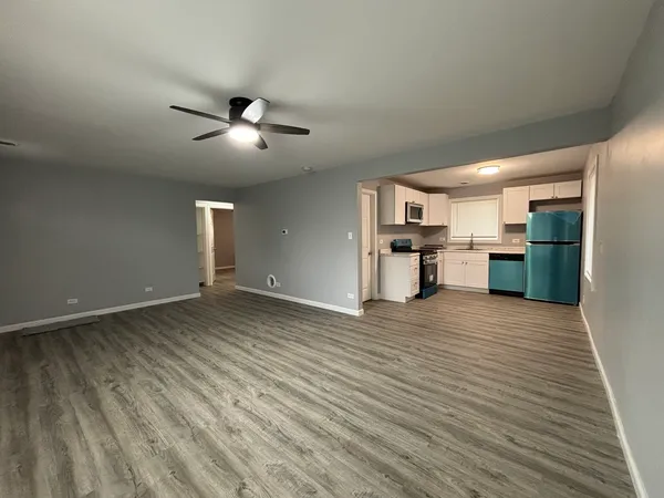 a view of an empty room with wooden floor and window
