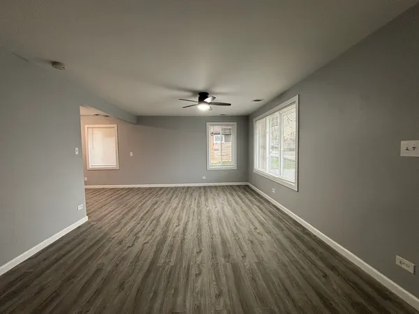 a view of an empty room with a window and wooden floor