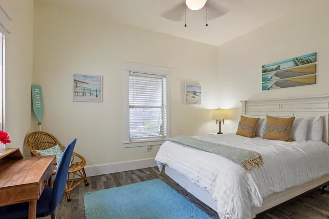 a bedroom with a bed a desk and chair with wooden floor