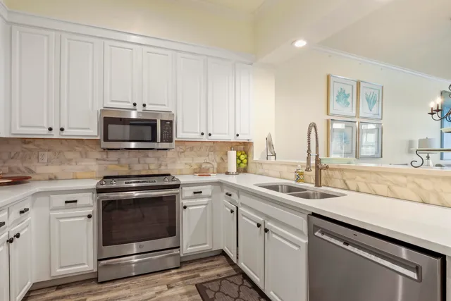 a kitchen with granite countertop white cabinets white stainless steel appliances and a sink