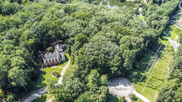 an aerial view of a house with swimming pool and large trees