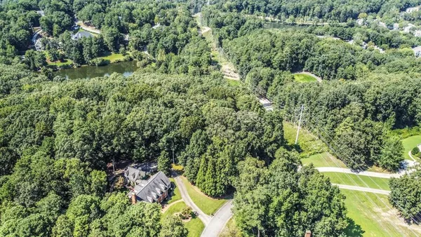 an aerial view of residential house with outdoor space and trees all around