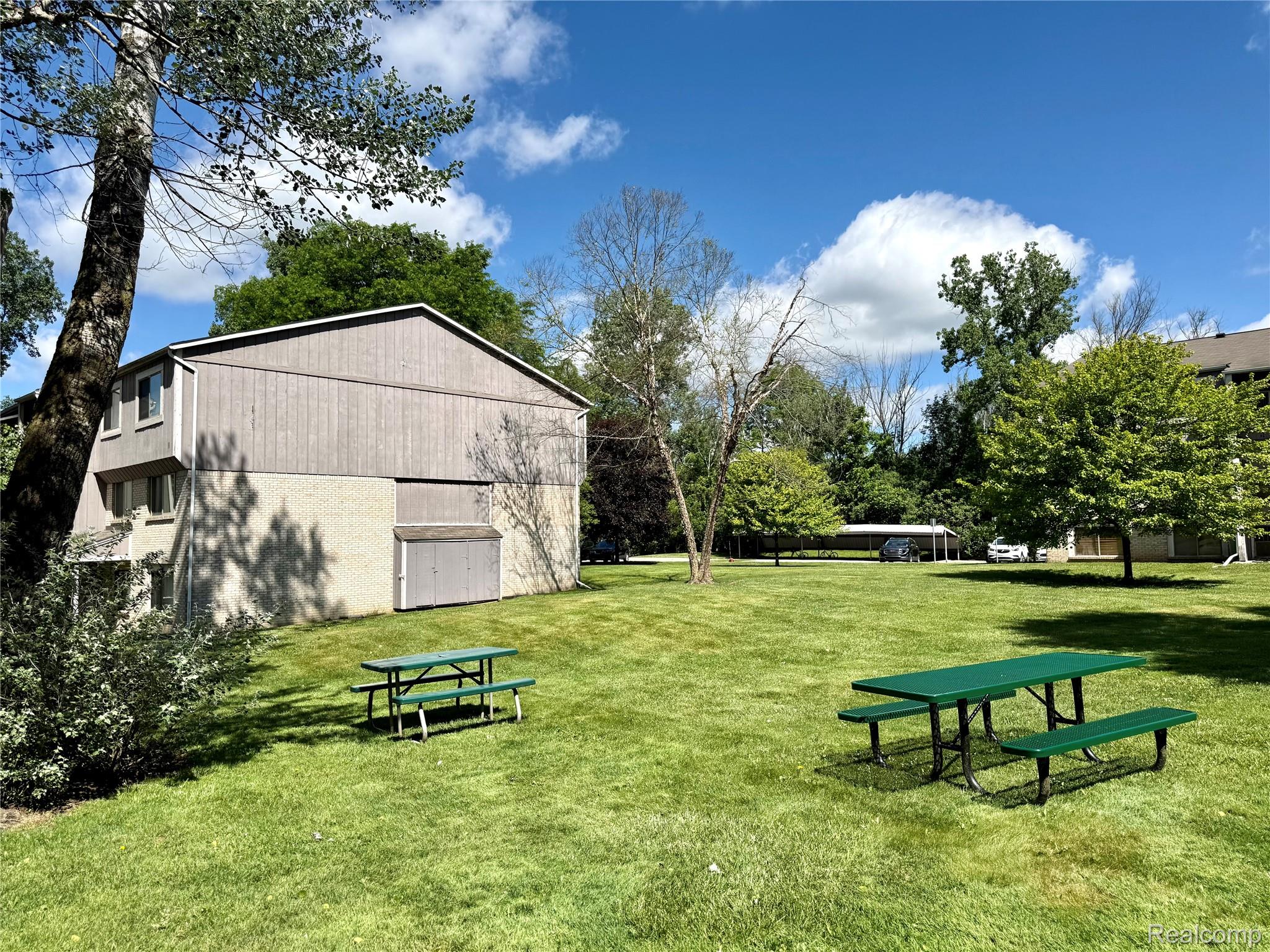 29870 West 12 Mile Road, Unit 703 Farmington, MI 48334 - Photo 34 of 40 Expansive green space featuring two green picnic tables on a manicured lawn