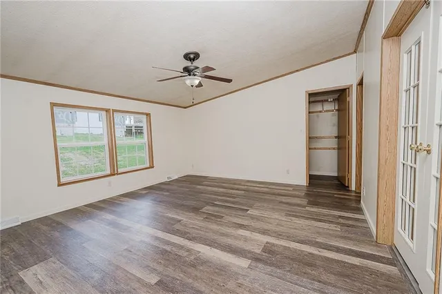 a view of empty room with wooden floor and fan