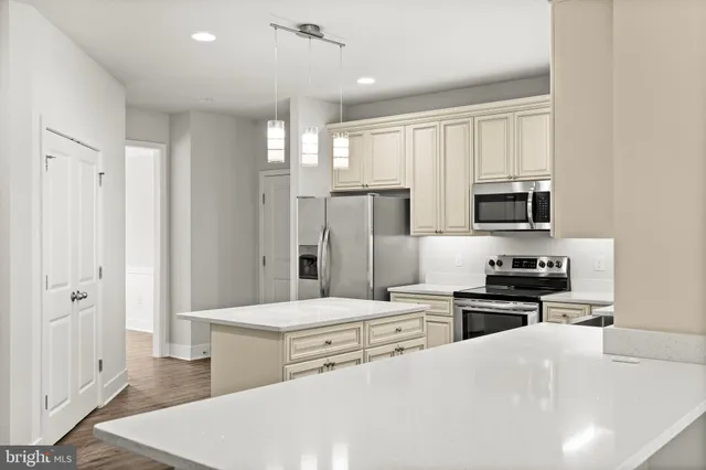 a large white kitchen with kitchen island a large island wooden floor and stainless steel appliances