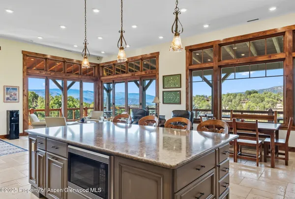 a kitchen with a stove a sink a dining table and chairs with the view of living room