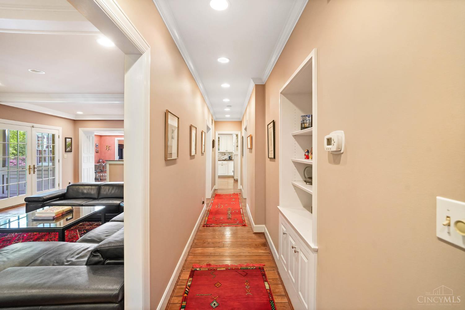 2780 Walsh Road Cincinnati, OH 45208 - Photo 20 of 68 This central hallway elegantly connects the main living spaces, creating effortless flow throughout the first floor. Lined with rich hardwood floors, crown molding and recessed lighting, this inviting corridor offers both function and charm, with built-in shelving adding warmth and character at every turn.