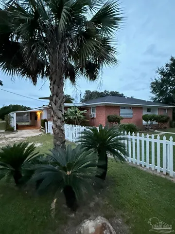 a backyard of a house with table and chairs plants and large tree