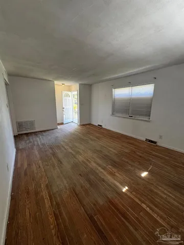 a view of an empty room and window and wooden floor