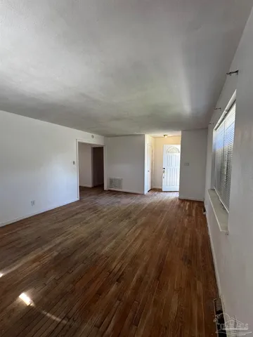 a view of an empty room and window and wooden floor