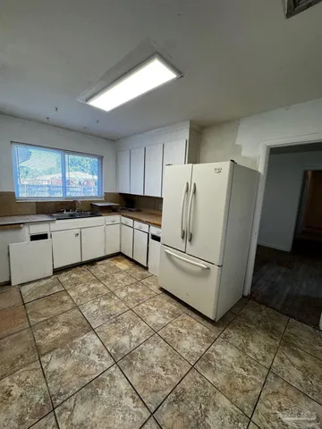 a large white kitchen with cabinets and a refrigerator