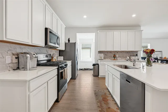 a kitchen with stainless steel appliances granite countertop a stove a sink a refrigerator with a dining table and chairs