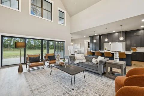 a living room with furniture a chandelier and a dining table with wooden floor