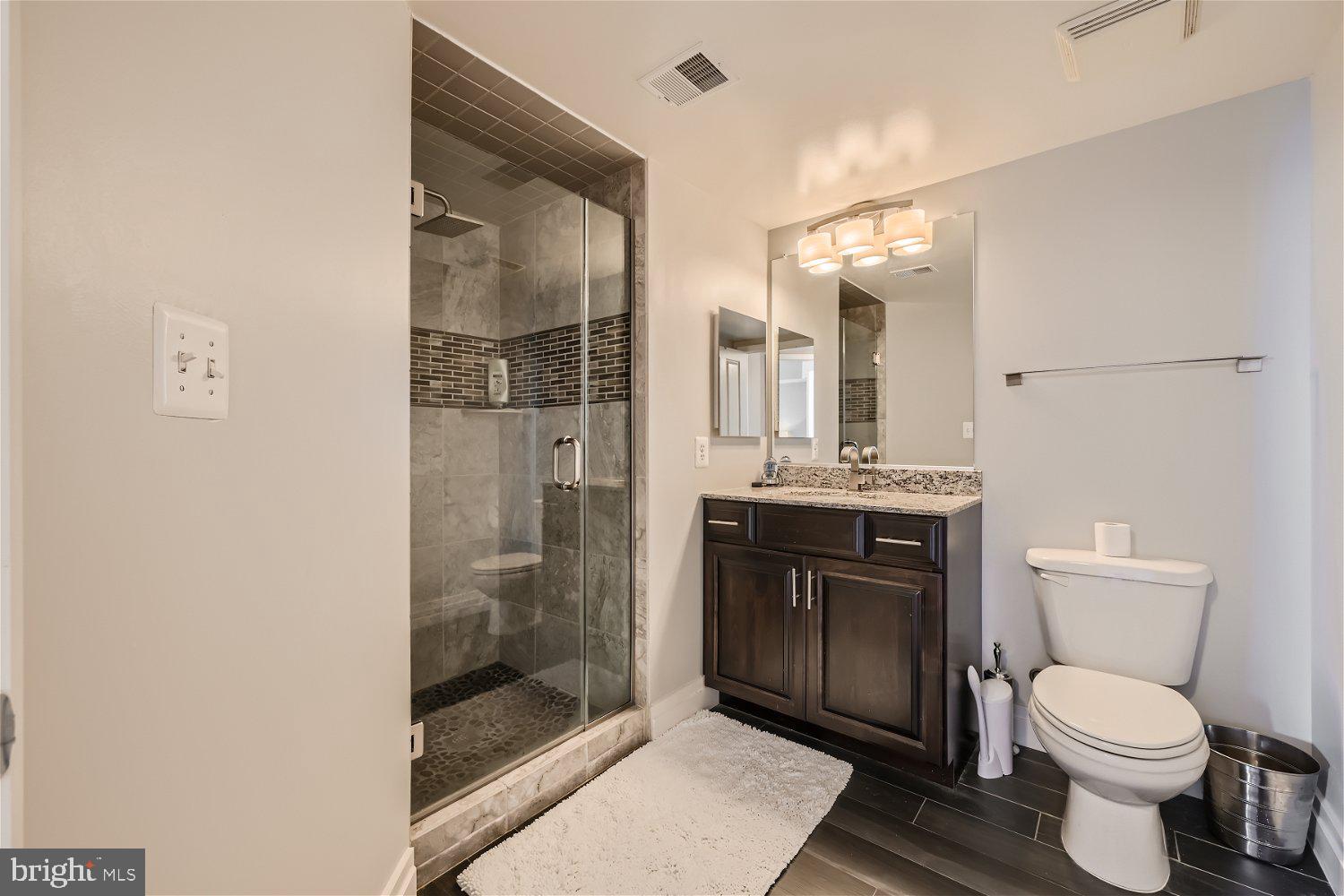 414 Water Street, Unit 2302 Baltimore, MD 21202 - Photo 14 of 34 a bathroom with a toilet a sink and glass door