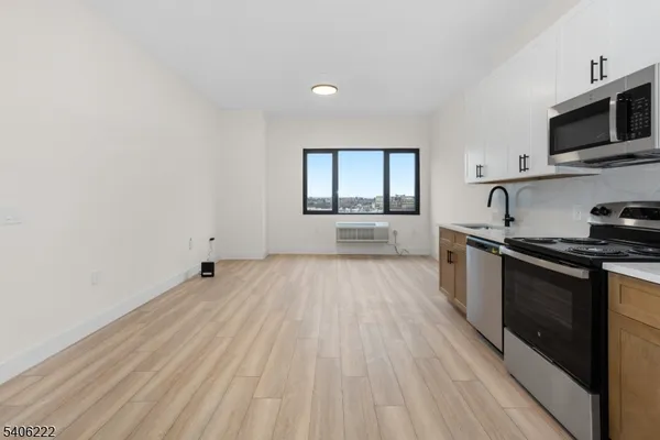 a kitchen with granite countertop a stove top oven a sink dishwasher and a microwave oven with white cabinets