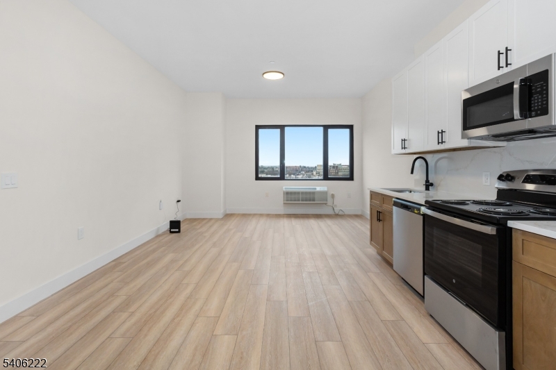 87-89 Mary Street, Unit 503 Paterson, NJ 07503 - Photo 6 of 14 a kitchen with granite countertop a stove top oven a sink dishwasher and a microwave oven with white cabinets
