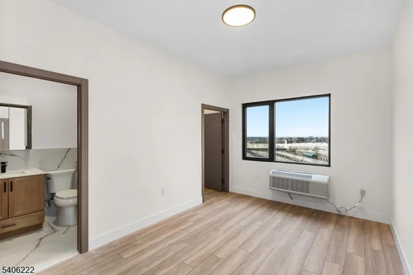a view of a kitchen and an empty room with wooden floor and a window
